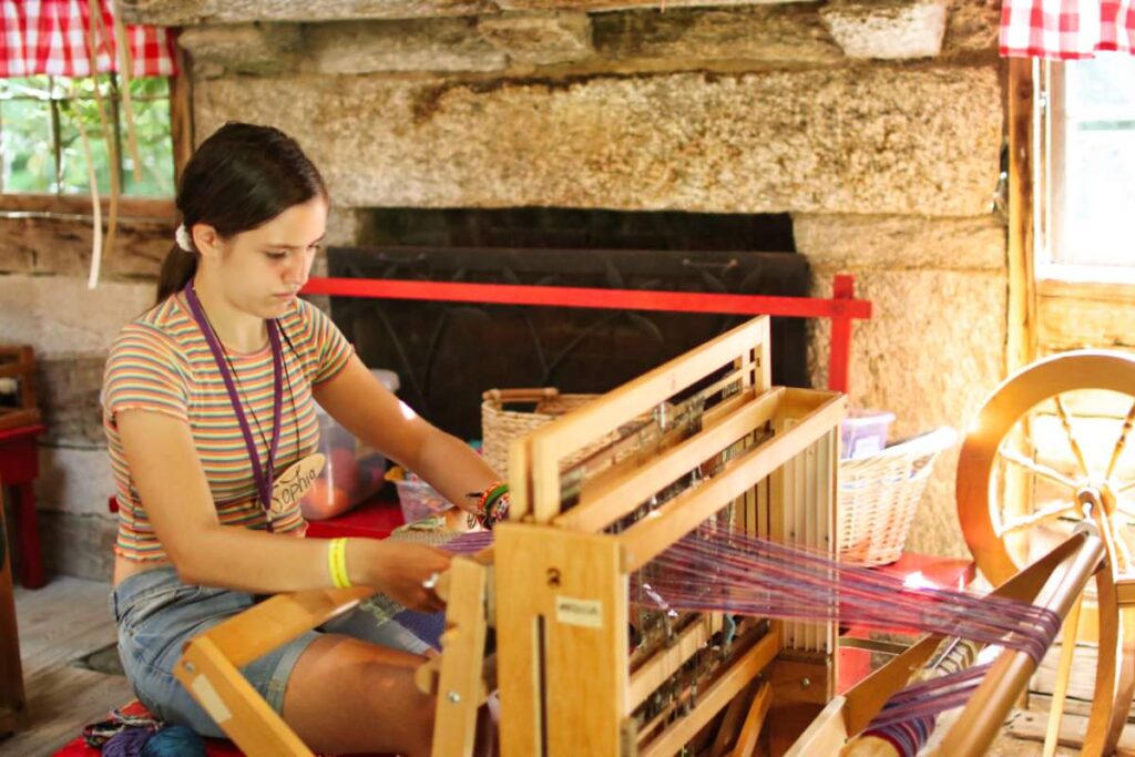 camp girl weaving on floor loom