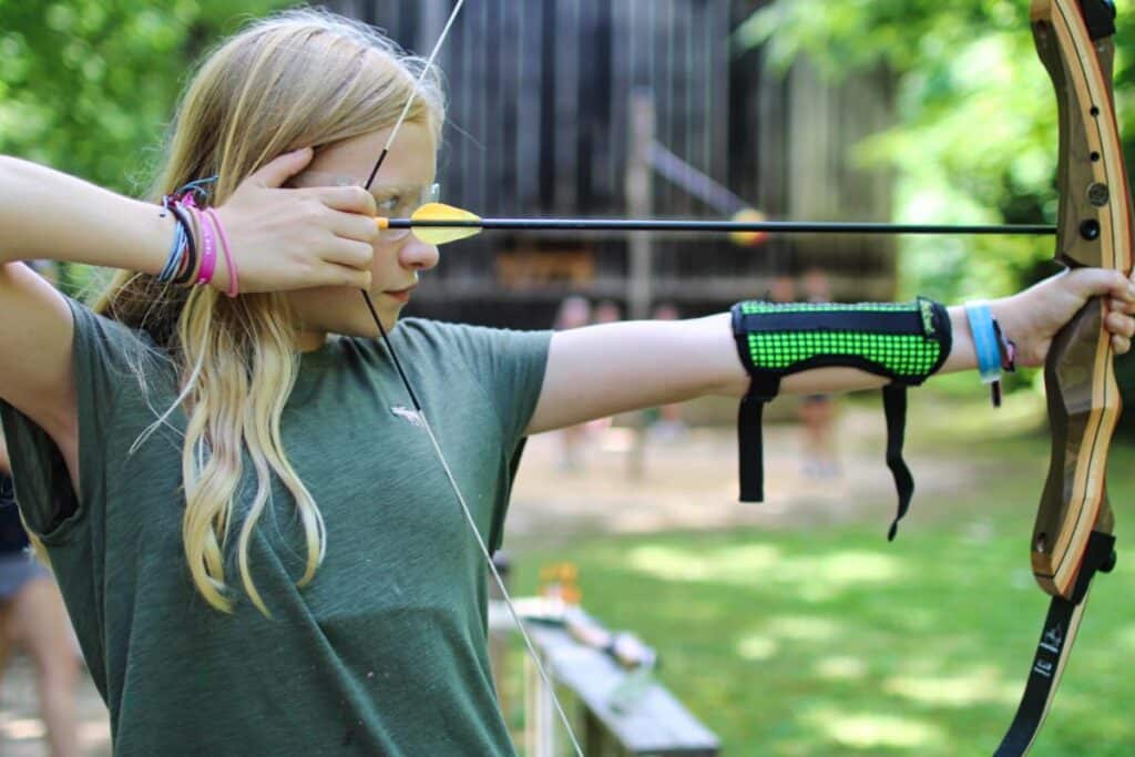 teen girl pulling arrow on bow