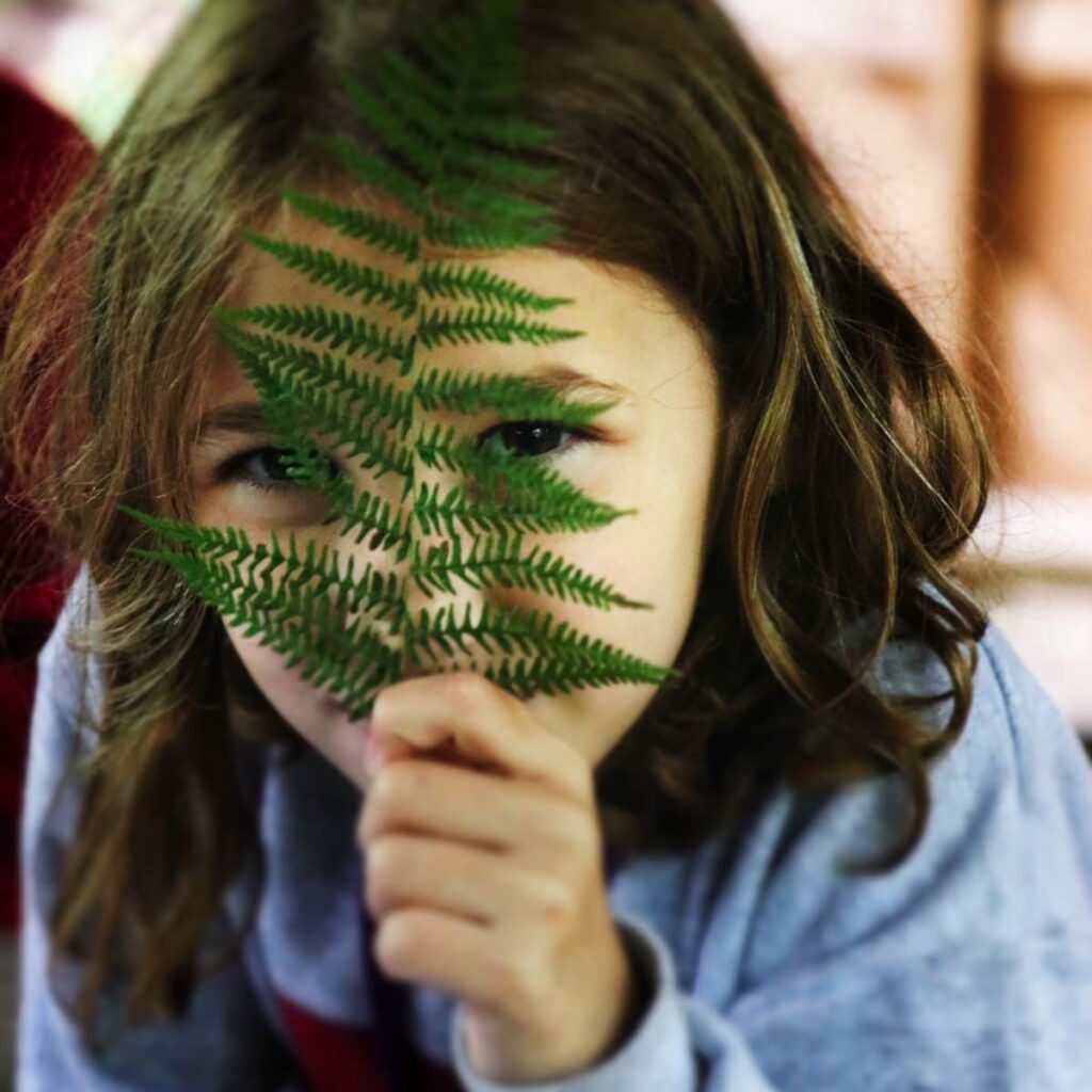 girl hiding behind a fern