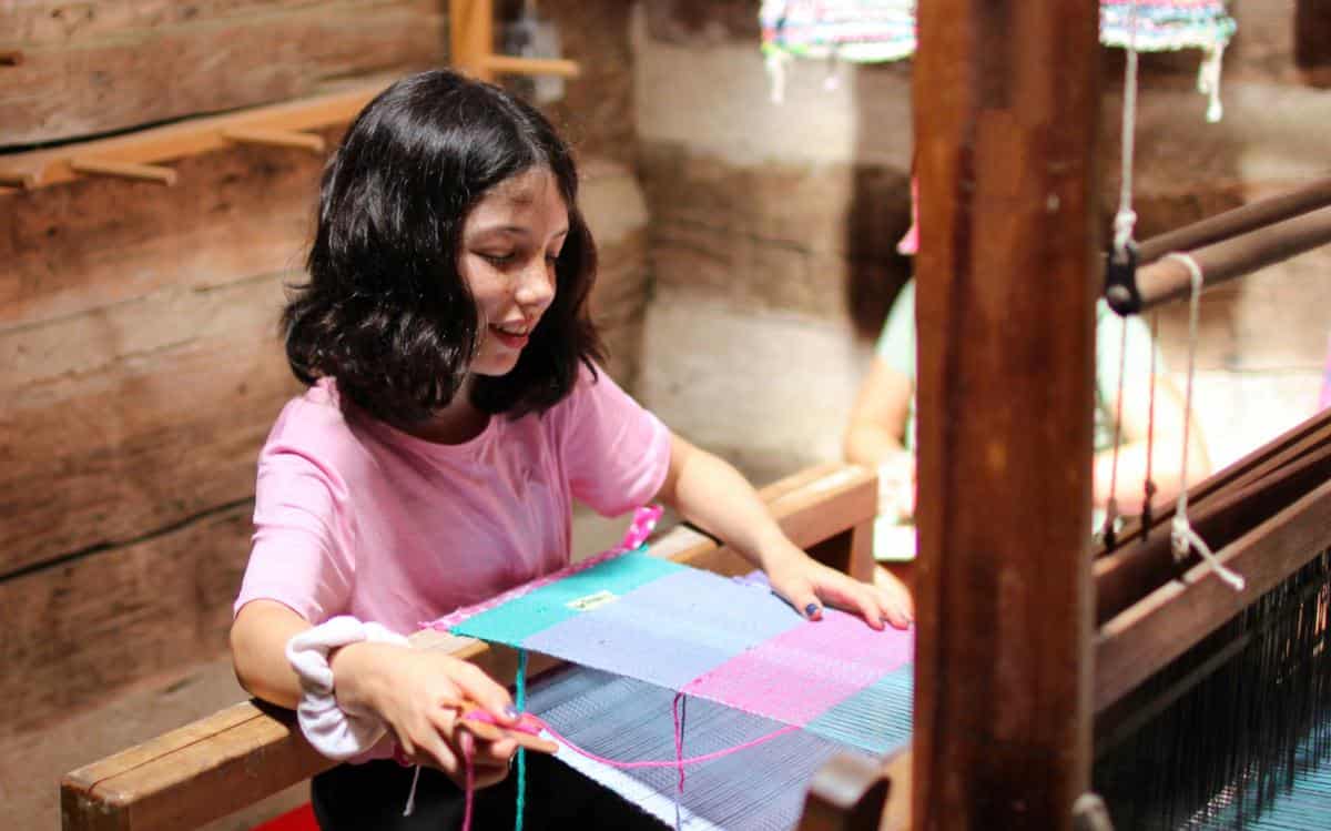 camp girls weaving on loom