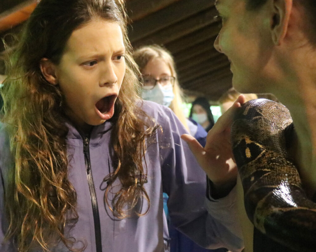 surprised camp girl touching a snake