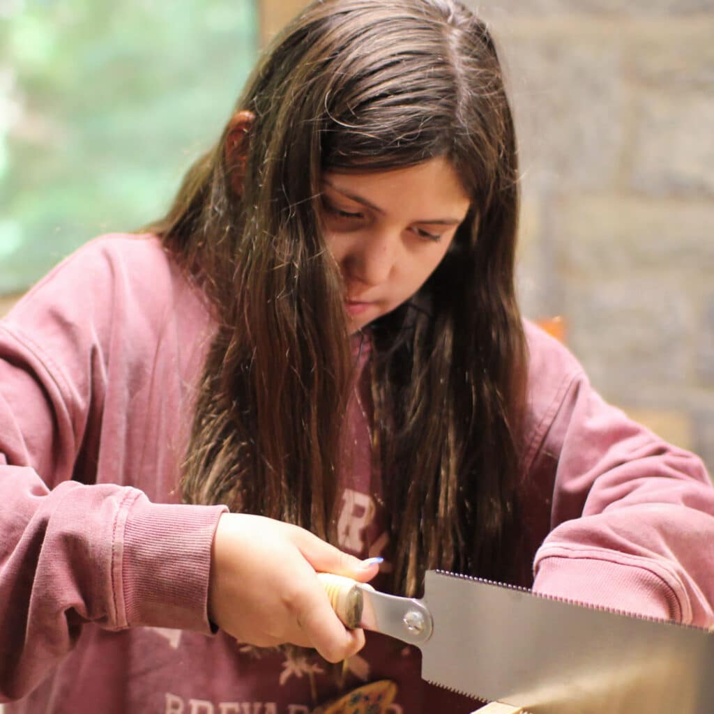 summer camp girl sawing wood