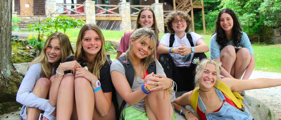 a group of summer camp girls sitting on rock enjoying camp life