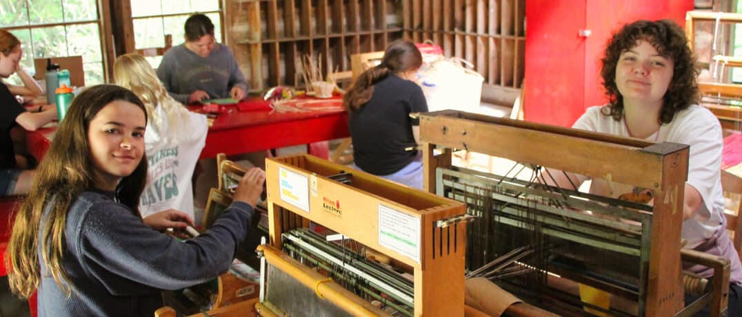 two teen girls working weaving looms