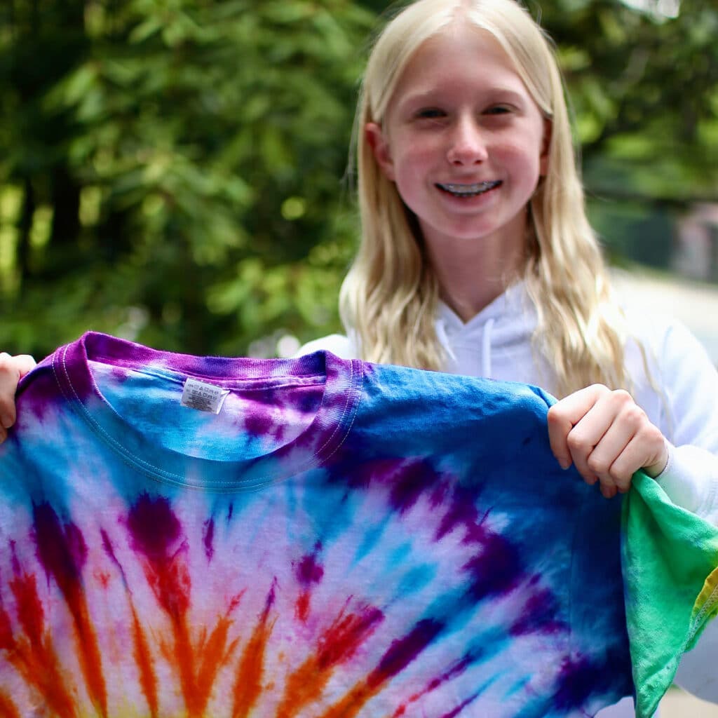 summer camp kid holding tie-dye t-shirt
