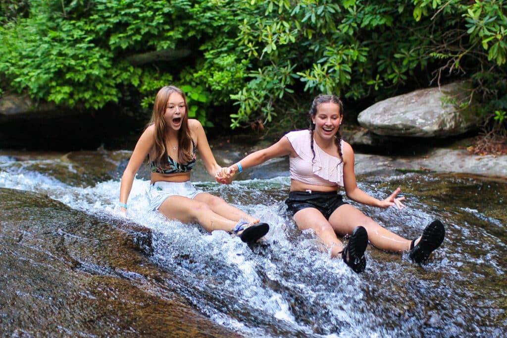 summer camp girls sliding down mountain creek