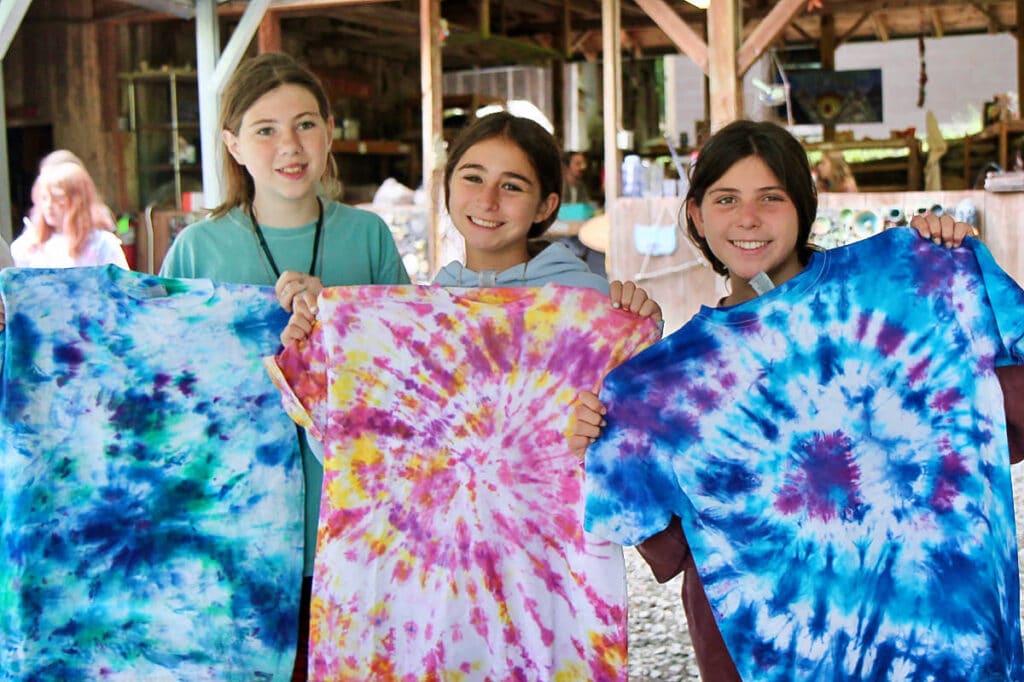 three girls holding their finished tie dye t-shirts