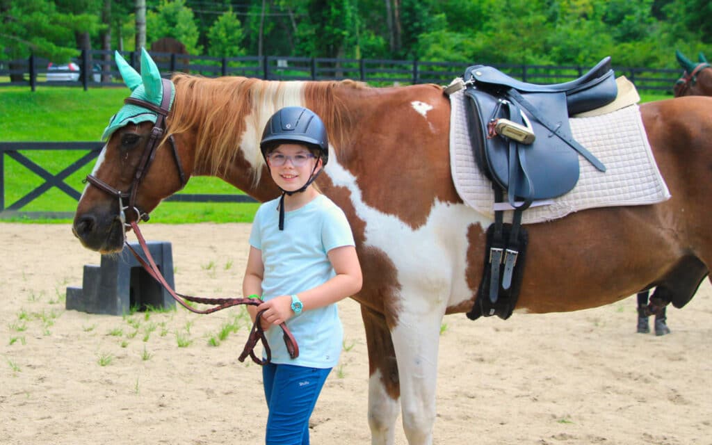 summer camp girl standing with horse