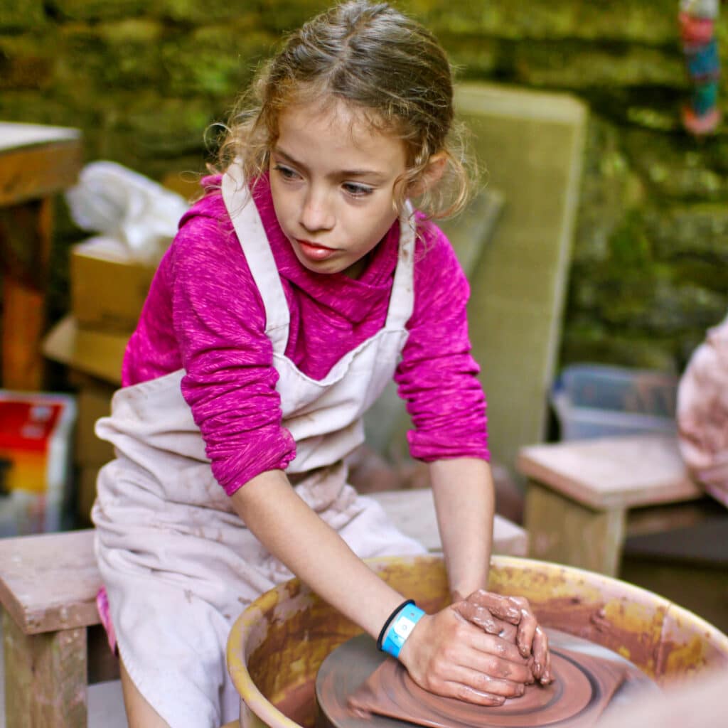 summer camp child throwing on pottery wheel