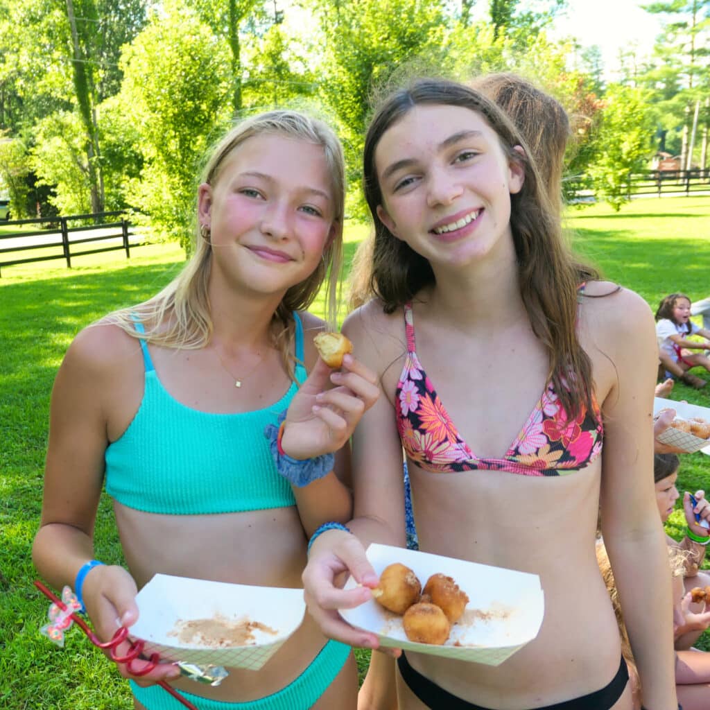 camp girls eating donuts at afternoon carnival