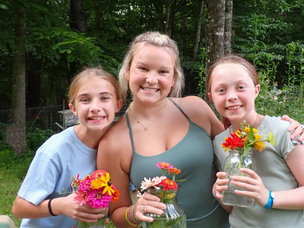 camp counselor and girls holding flowers