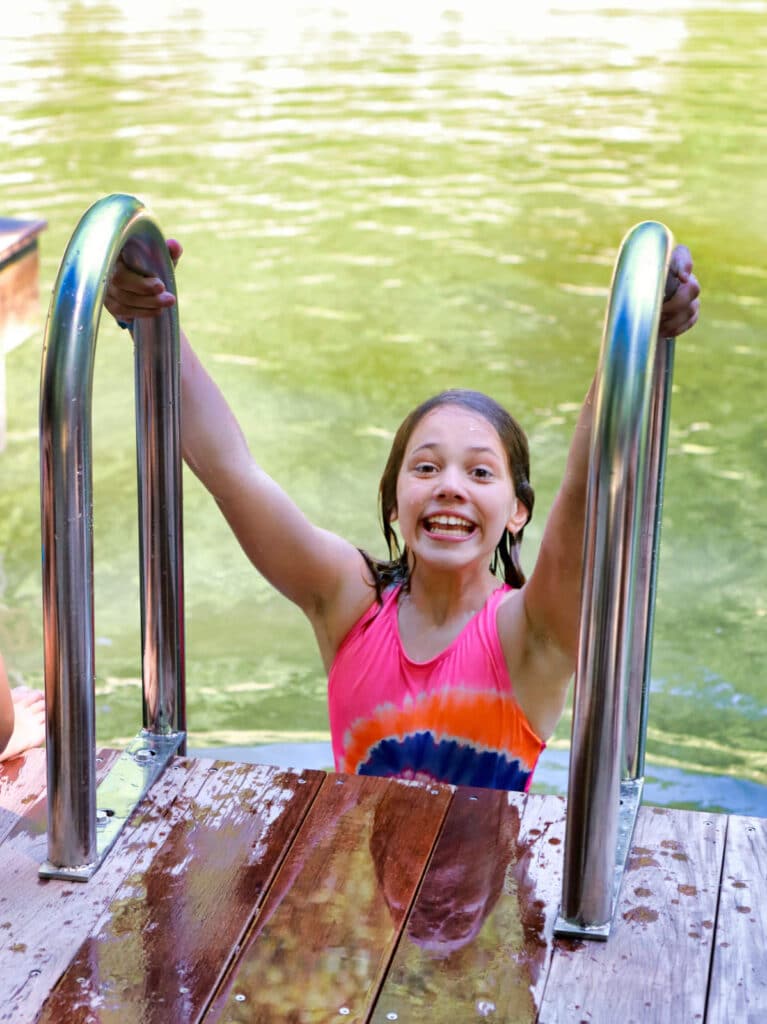 girl coming up ladder at summer camp lake