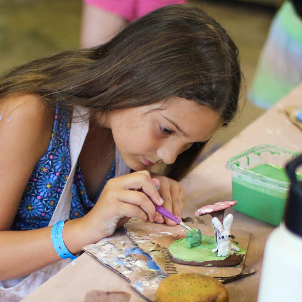 child glazing pottery sculpture