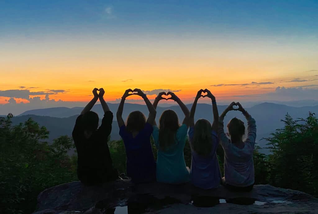 camp girls making hearts on sunset