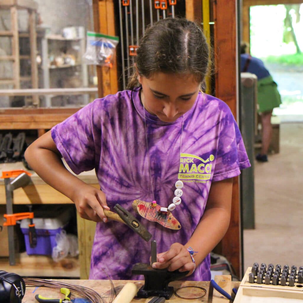 camp girl hammering metal for jewelry
