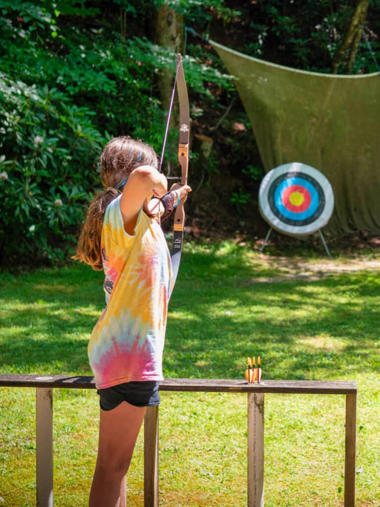 girl shooting archery at summer camp