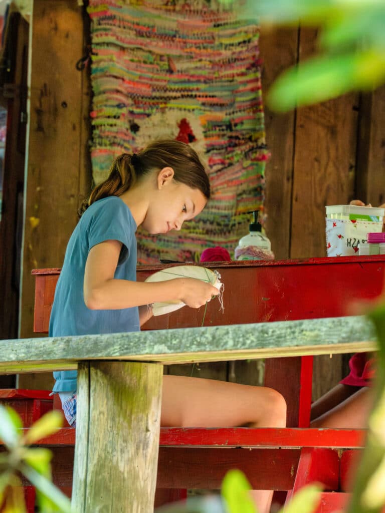 young summer camp girl crafting needlepoint