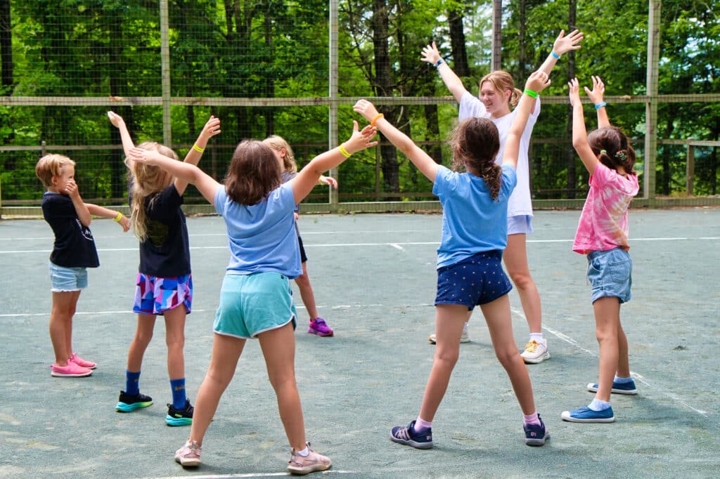 summer camp for kids tennis class with counselor leading