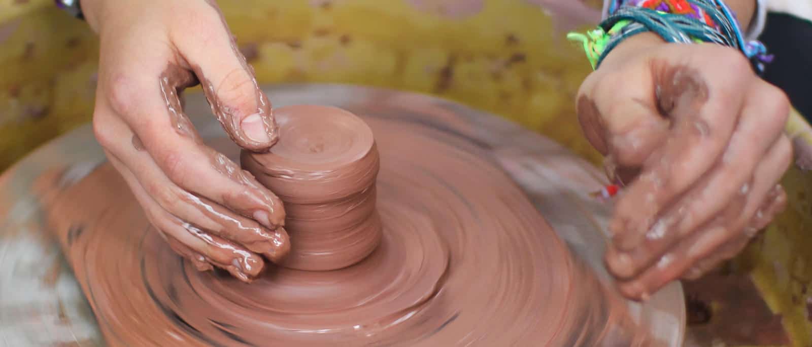 girl camp teen's hands throwing on the pottery wheel