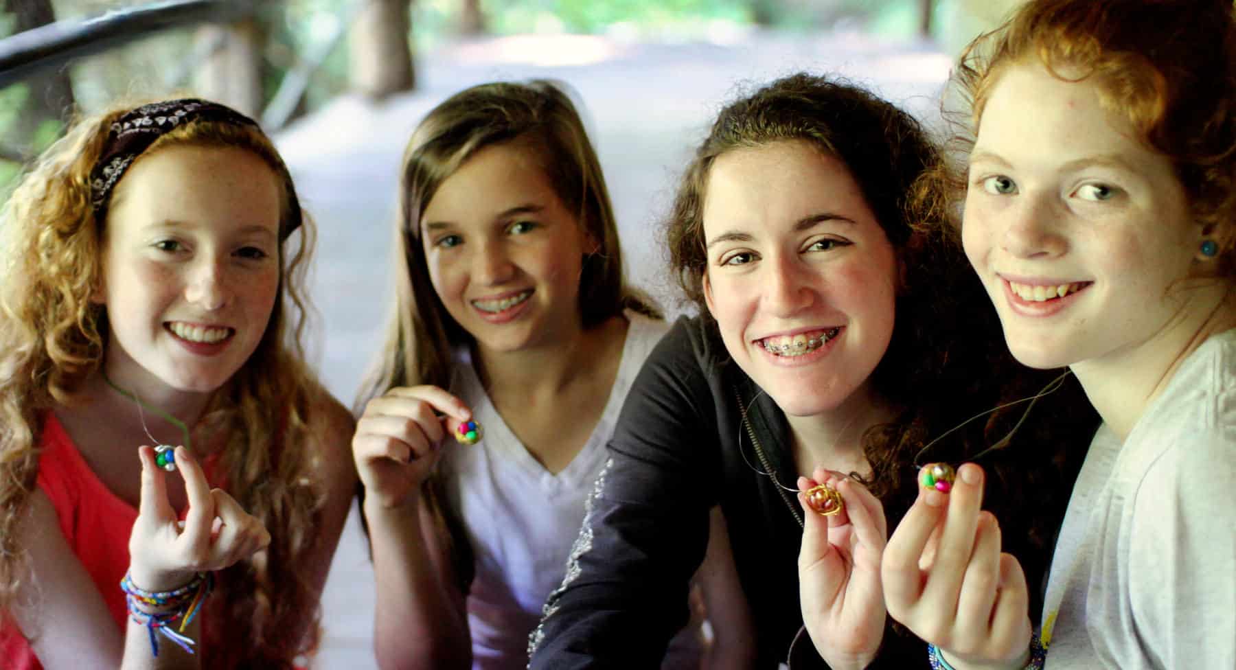 camp girls showing beaded necklaces they made